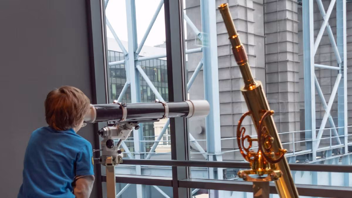 Chłopiec patrzący przez teleskop w Łódź EC1 – Planetarium, Naukowy Świat i Retro Gry podczas wycieczki szkolnej.