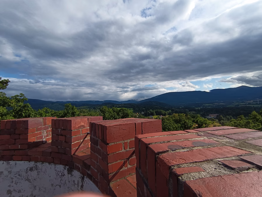 Ceglane zwieńczenie wieży Zamku Księcia Henryka z widokiem na panoramę Karkonoszy.